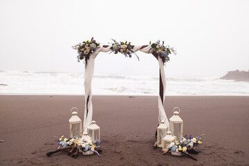 Beautiful floral arch with lanterns for a wedding on a beach