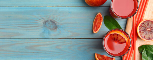 Tasty sicilian orange juice and fruits on light blue wooden table, flat lay with space for text....