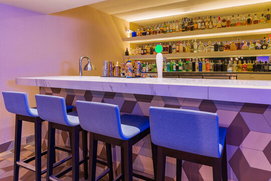 Modern bar counter with stools and different bottles of alcohol