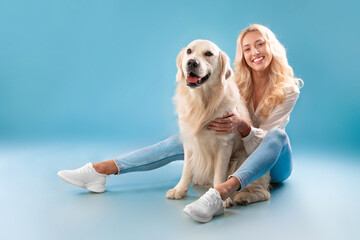 Young woman posing with her dog at blue studio