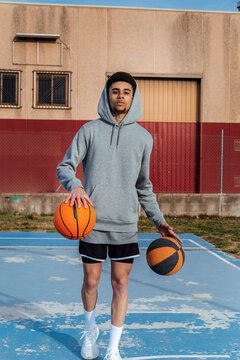 Hispanic man dribbling basketballs on playground