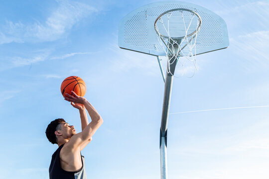 Faceless man throwing ball in hoop
