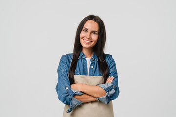 Young smiling caucasian female barista bar tender coffee maker woman in apron selling coffee hot beverage tea with arms crossed isolated in white background. - obrazy, fototapety, plakaty