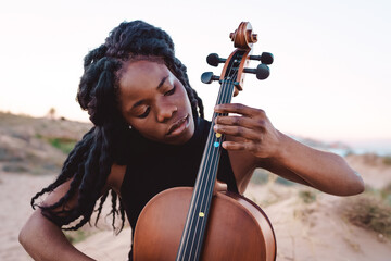 Black woman play cello on beach