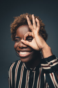 Smiling black woman showing OK gesture in studio