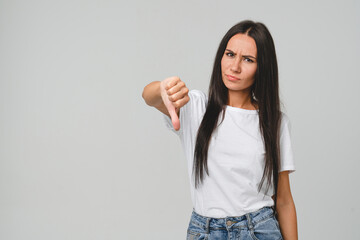 Negative opinion concept. Caucasian young woman in white T-shirt showing thumb down for...