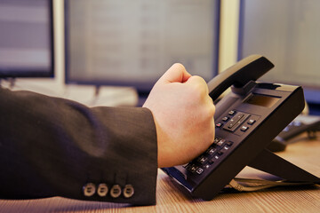 Angry businessman in a suit talking on a landline phone in the office, man fist close-up