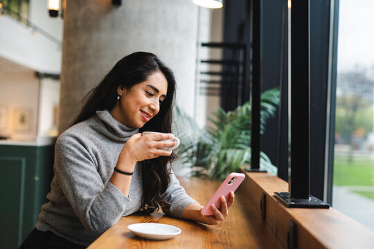 Businesswoman drinking coffee and browsing smartphone