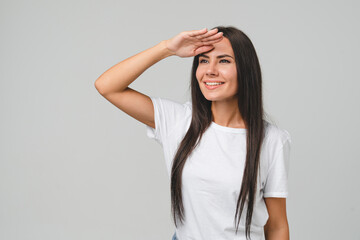 Young caucasian woman girl in white T-shirt looking far away forward in future, copy space free space for adverts isolated in grey background