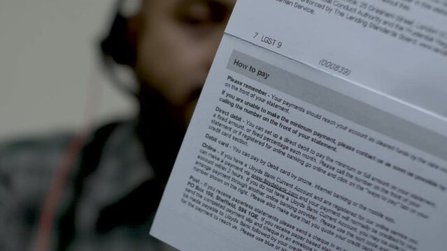Back View Of Credit Card Statement With How To Pay Instructions With Bokeh Background Of Adult Male Shaking Head