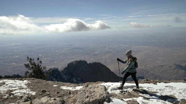Female hiker walks on trail overlooking distant Albuquerque New Mexico