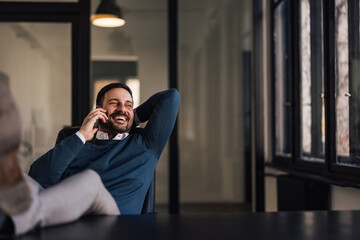 Fototapeta premium Happy businessman, enjoying his break at work, making a phone call, laughing.
