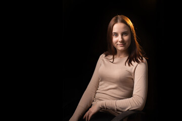 Young positive woman looks at the camera. Dark background. Friendly face. Looks into the camera. Place for text.