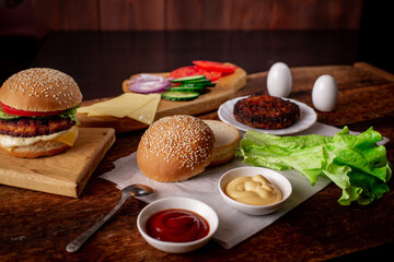 Hamburger day. Cooking hamburger or cheeseburger. Different ingredients for a classic hamburger. Place for text. Wooden background.