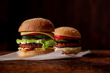 Two hamburgers on a wooden background. Big and small cheeseburger. Hamburger day.