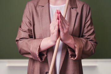 Woman teacher folded her hands in prayer gesture on school blackboard in the classroom