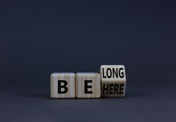 Be here belong symbol. Turned a wooden cube and changed concept words Be here to Belong. Beautiful grey background. Business, belonging and be here belong concept. Copy space.