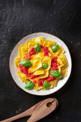 Ravioli with tomato sauce and fresh basil leaves, shot from above