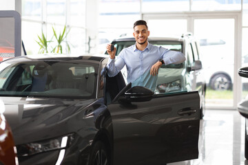 Fototapeta na wymiar Wealthy arab guy businessman buying new car, showing key
