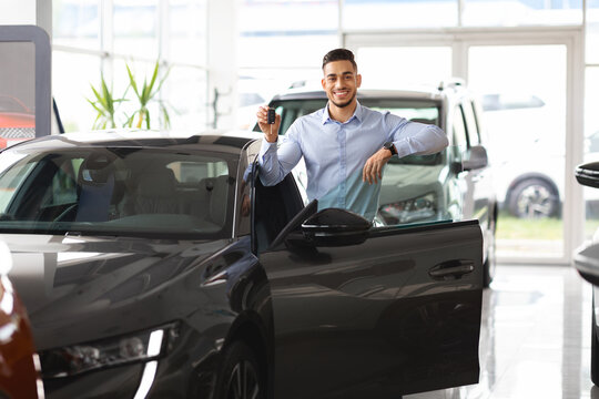 Wealthy arab guy businessman buying new car, showing key