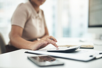 Working on her business earnings and expenses. Closeup shot of an unrecognisable businesswoman calculating finances in an office.