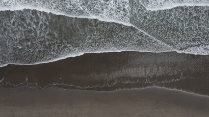Luchtfoto van de golvende zee die het zandstrand aan de kust raakt