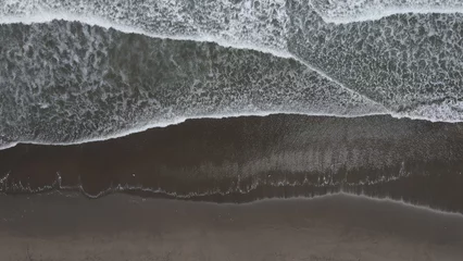 Fotobehang Donkergrijs Luchtfoto van de golvende zee die het zandstrand aan de kust raakt