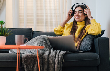 Tranquil young caucasian girl, watching show on laptop, putting headphones on.