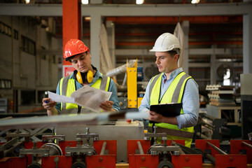 Two young engineers Testing and verifying the operation of the machines forming metal sheet tiles