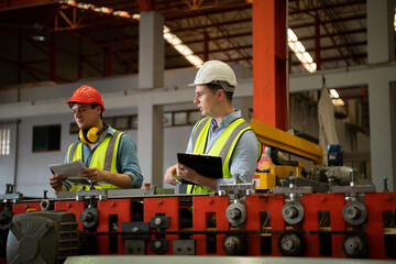 Two young engineers Testing and verifying the operation of the machines forming metal sheet tiles