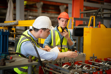 Two young engineers Testing and verifying the operation of the machines forming metal sheet tiles