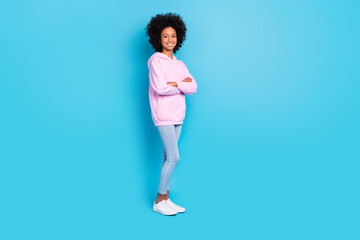 Full size photo of young cheerful pretty girl crossed hands standing isolated over blue color background