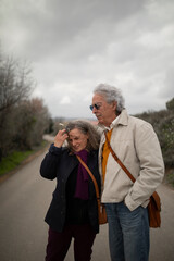 A couple, man and woman, retired couple, 60 and 70 years old, with gray hair, enjoy a romantic walk in spring, in a rural area of the Campo de Borja, province of Zaragoza, Aragon, Spain