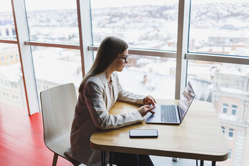 woman in a jacket smiling and working on a laptop