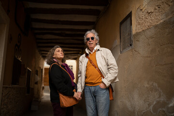 A couple, man and woman, 60 and 70 years old, with gray hair, do rural tourism in a small village,...