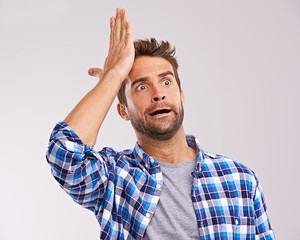 Duh. Studio shot of a young man looking forgetful against a gray background.