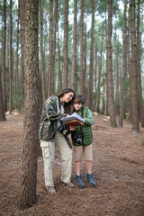 Happy family with cameras walking in forest. Dark-haired mother and son in coats getting ready to take pictures, discussing route. Parenting, family, leisure concept