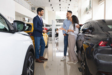 Middle eastern couple having conversation with sales assistant, buying car
