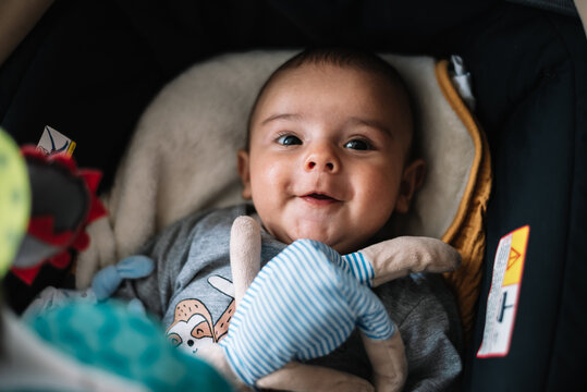 Baby lying in the carriage. Smiling next to her teddy bear.