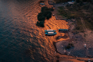 Bird's eye view of boats moored at the rocky shore of blue Lake Atitlan in Guatemala at sunset
