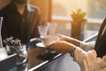 Woman hands holding hot cup of tea or coffee in modern cafe coffee shop. Enjoying hot drink close up.