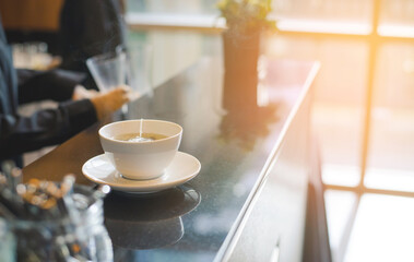 White cup of hot tea waiting for customer on counter bar in modern cafe coffee shop. Time of Tea Break.