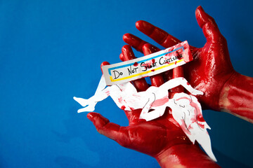 Bloody hands hold a paper cutout of a woman's body and a sign with a request not to shoot...