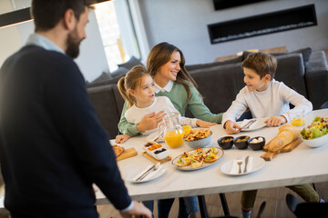 Young happy family talking while having breakfast at dining table