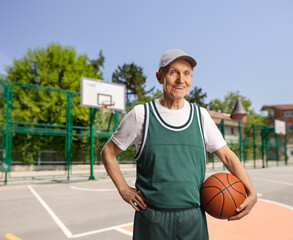 Smiling elderly man holding a basketball on a basketball court