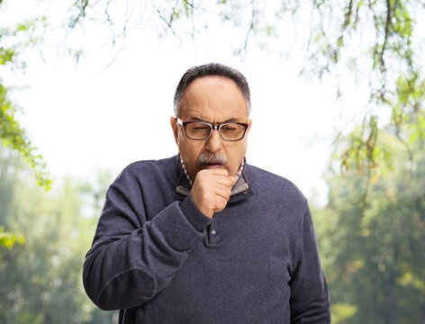 Mature man caughing in a park