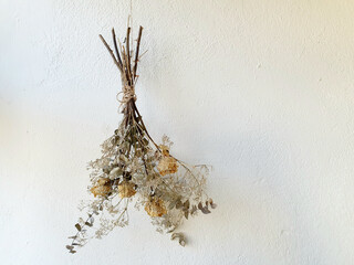 Dried orange rose bouquet hanging upside down with a white painted wall background