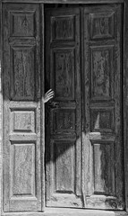 Black and white image of hand and the old wooden door