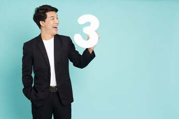 Young Asian business man showing number 3 or three isolated on green background