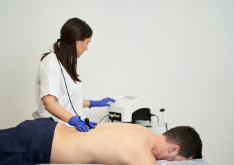Obraz na płótnie Canvas A female physiotherapist giving diathermy treatment on the patient's back.